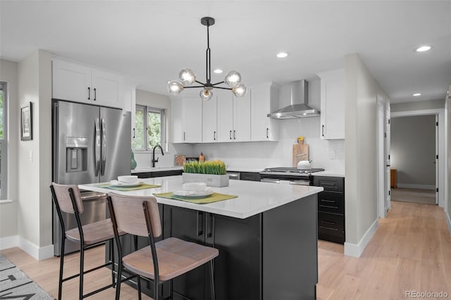 kitchen featuring wall chimney exhaust hood, white cabinetry, light countertops, decorative backsplash, and recessed lighting