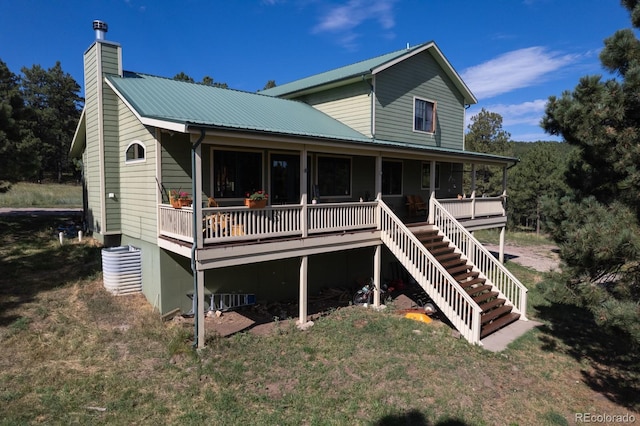 exterior space featuring a front lawn, a chimney, stairway, and metal roof