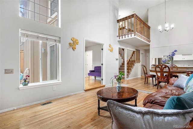 living room with hardwood / wood-style flooring, plenty of natural light, a chandelier, and a high ceiling