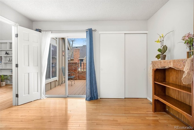 doorway to outside with light hardwood / wood-style floors and a textured ceiling