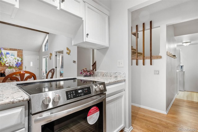 kitchen featuring lofted ceiling, light hardwood / wood-style flooring, light stone counters, white cabinets, and stainless steel electric range oven