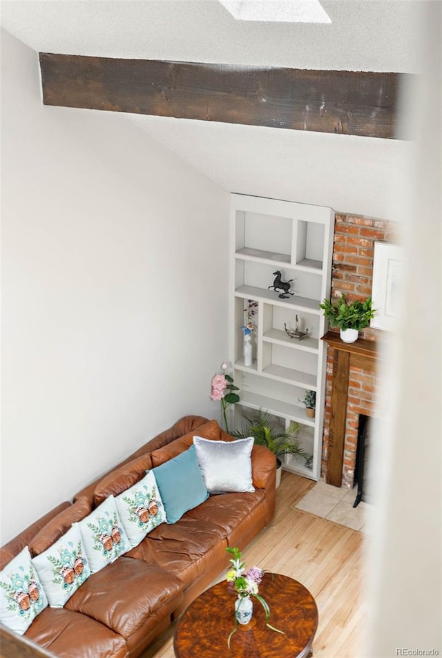 living room with a brick fireplace, a skylight, hardwood / wood-style floors, and built in features