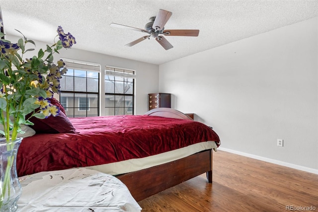 bedroom with ceiling fan, hardwood / wood-style flooring, and a textured ceiling