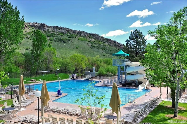 view of swimming pool with a patio, a water slide, and a mountain view