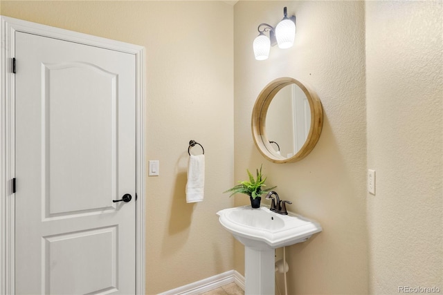 bathroom featuring baseboards and a sink