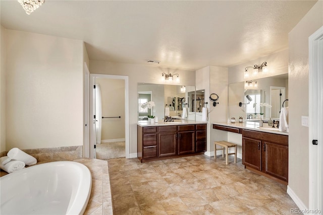 bathroom featuring visible vents, two vanities, a bath, and baseboards