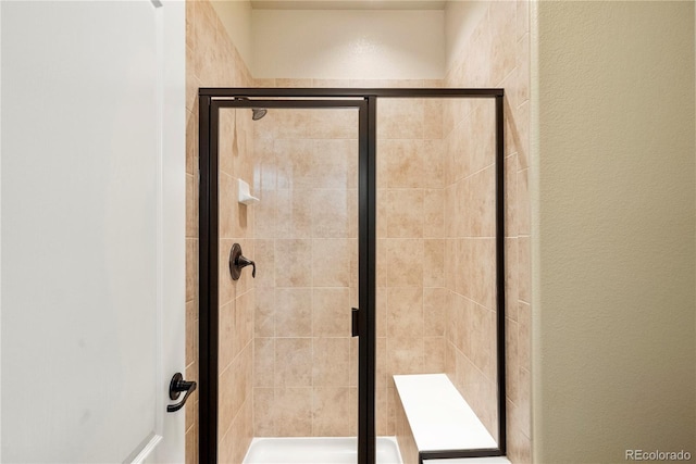 bathroom with a shower stall and a textured wall