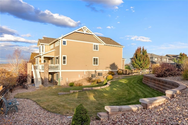 rear view of house featuring stairs, a lawn, and fence