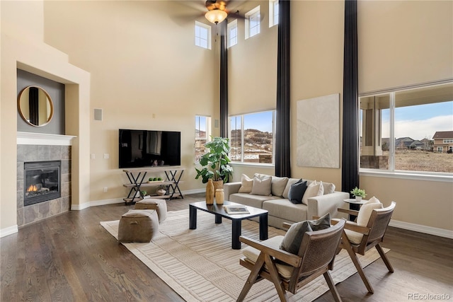 living room with baseboards, wood finished floors, and a tiled fireplace