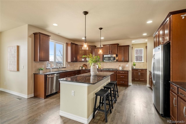 kitchen with tasteful backsplash, a center island, dark wood-type flooring, stainless steel appliances, and a sink