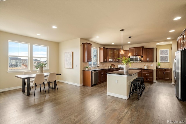 kitchen with plenty of natural light, dark wood-style flooring, stainless steel appliances, tasteful backsplash, and a center island