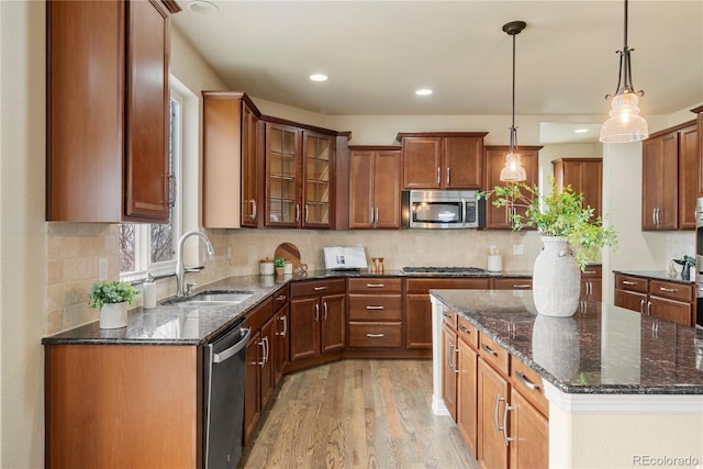 kitchen with light wood finished floors, backsplash, stainless steel appliances, and a sink