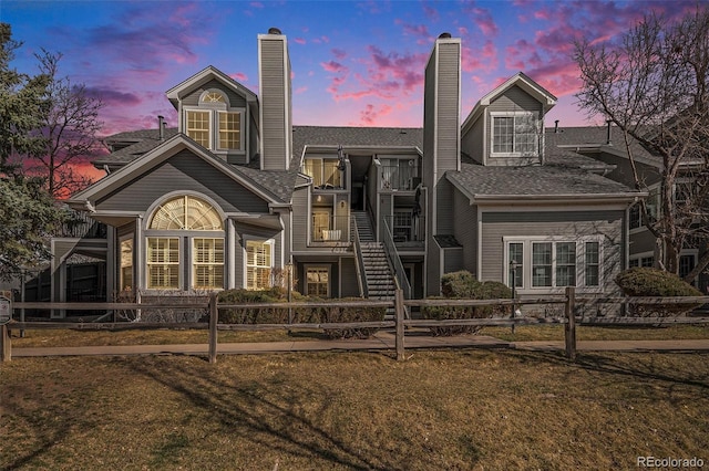 view of front of house with a fenced front yard, a chimney, and stairs