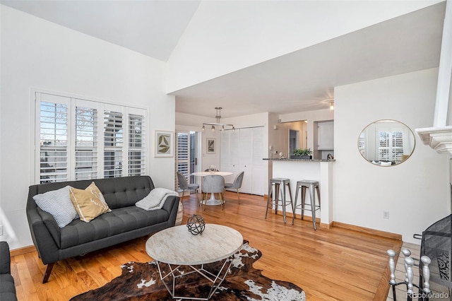 living room with baseboards, high vaulted ceiling, and wood finished floors