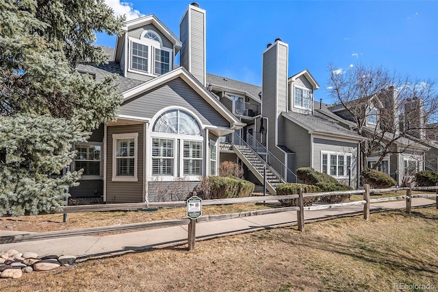 view of front of home with a fenced front yard, a chimney, and stairway