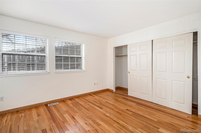 unfurnished bedroom with visible vents, baseboards, a closet, and light wood-style flooring