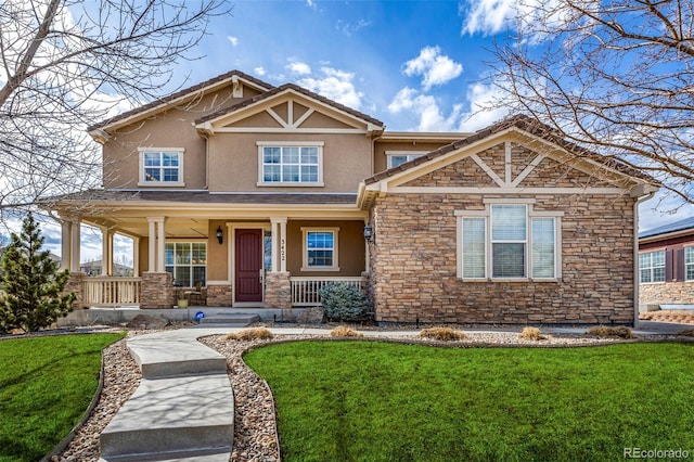 craftsman-style house featuring stone siding, covered porch, a front lawn, and stucco siding