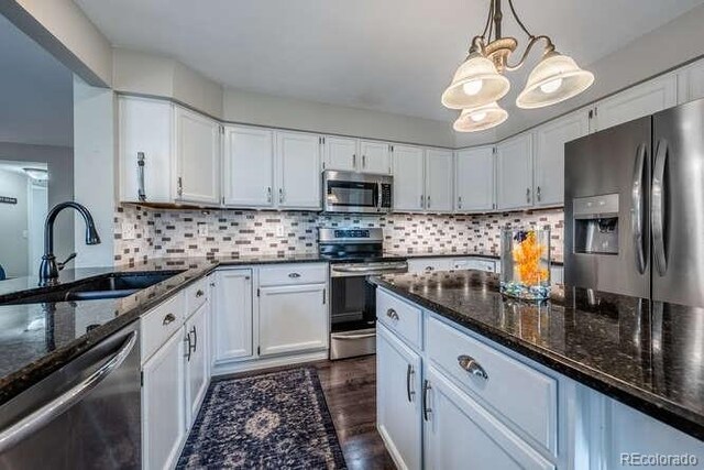 7176 S Pierson St, Littleton, CO 80127 - kitchen featuring stainless steel appliances, a sink, dark stone countertops, white cabinets, and dark wood-type flooring