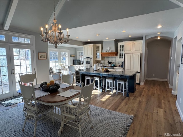 dining space featuring vaulted ceiling, dark hardwood / wood-style floors, an inviting chandelier, and french doors