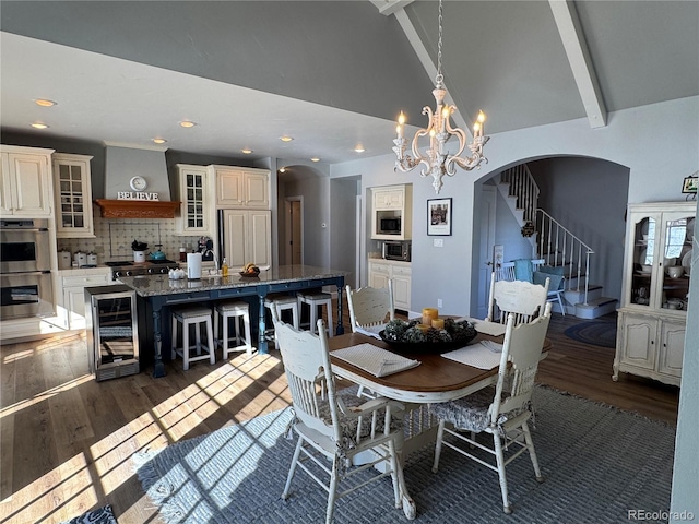 dining area with dark hardwood / wood-style floors, a chandelier, beverage cooler, and beamed ceiling