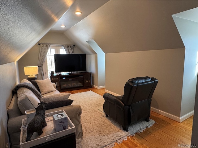 living room with lofted ceiling, a textured ceiling, and light wood-type flooring