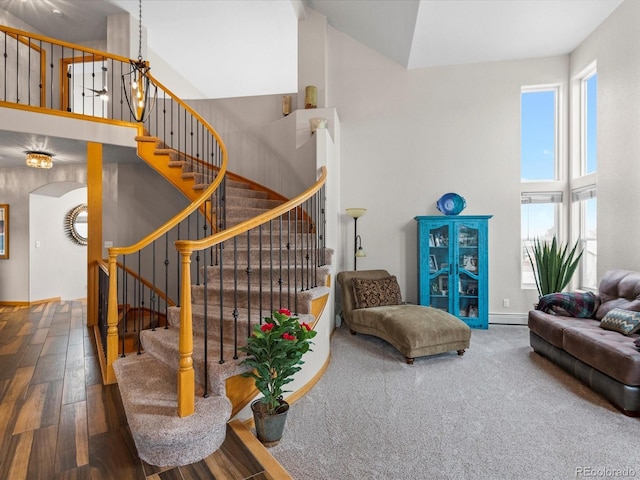 living area with arched walkways, stairway, a high ceiling, and wood finished floors