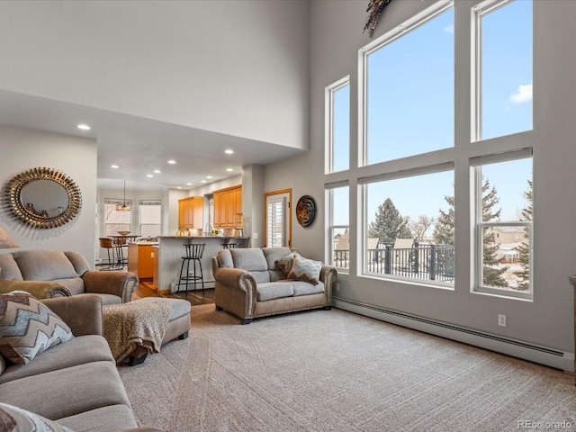 carpeted living room featuring recessed lighting, a high ceiling, and baseboard heating