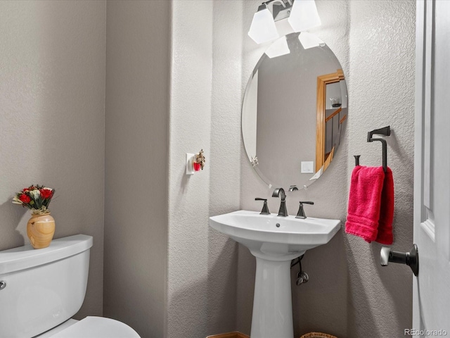 bathroom featuring a textured wall and toilet