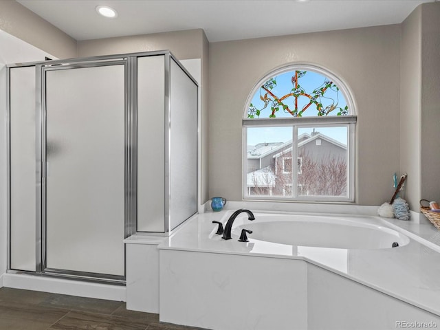 full bath featuring a shower stall, a bath, and wood finished floors