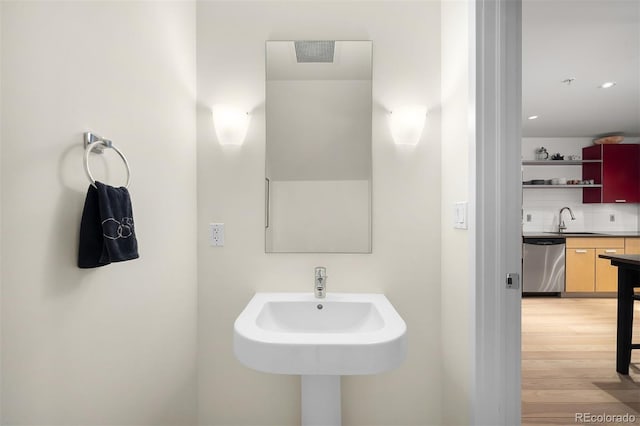 bathroom with sink, decorative backsplash, and hardwood / wood-style floors