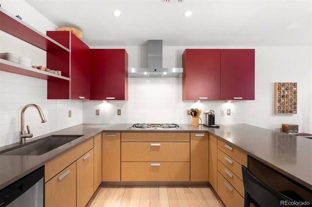 kitchen featuring wall chimney range hood, stainless steel dishwasher, a sink, gas stovetop, and backsplash