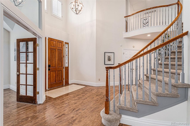 entrance foyer featuring baseboards, a high ceiling, an inviting chandelier, and wood finished floors