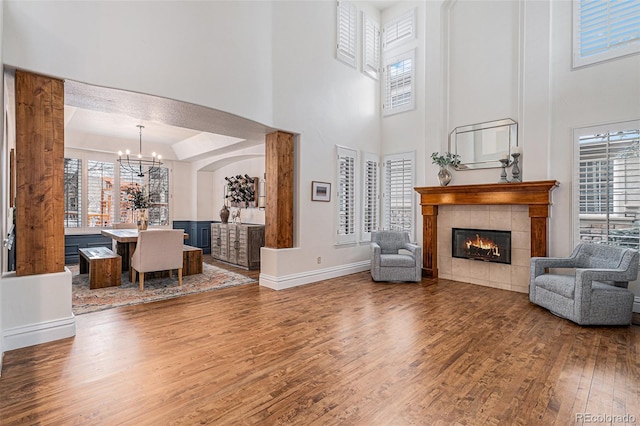 living room featuring a tiled fireplace, an inviting chandelier, plenty of natural light, and wood finished floors