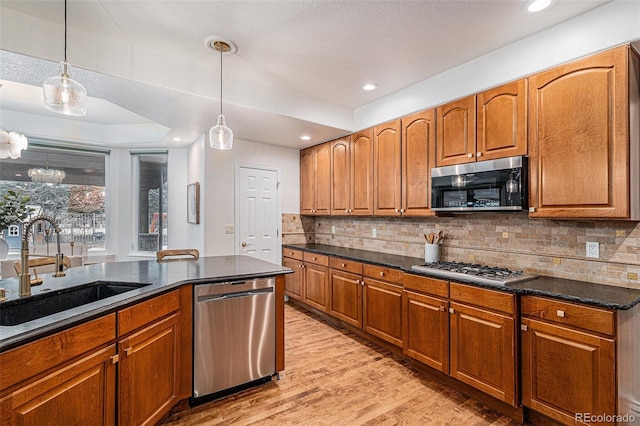 kitchen featuring a sink, tasteful backsplash, light wood-style floors, and appliances with stainless steel finishes