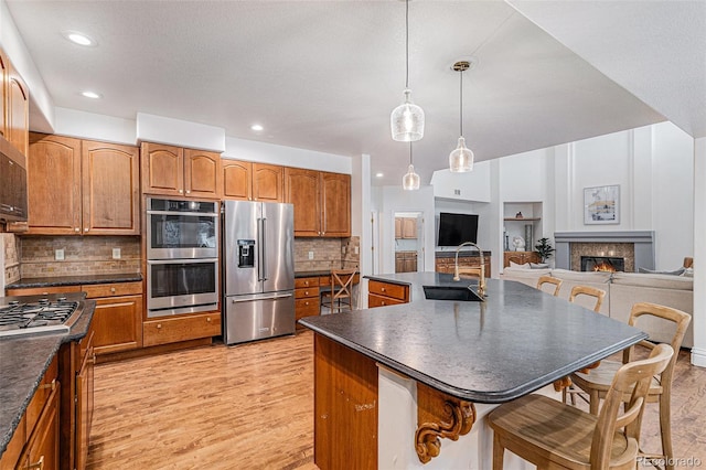 kitchen with a sink, a kitchen breakfast bar, dark countertops, and appliances with stainless steel finishes