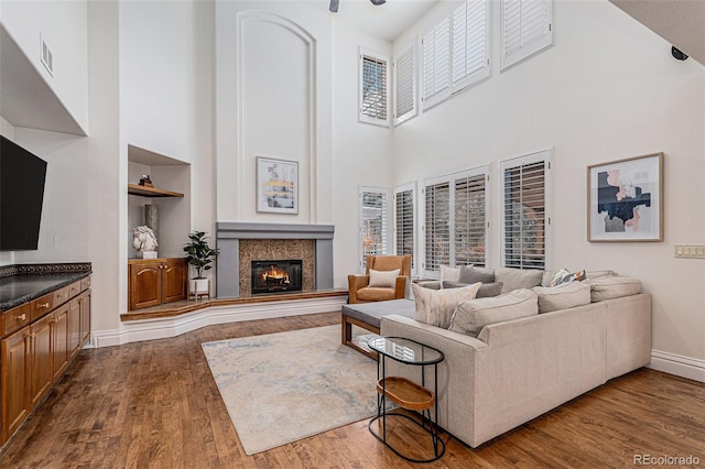 living room with dark wood finished floors, built in shelves, a healthy amount of sunlight, and visible vents