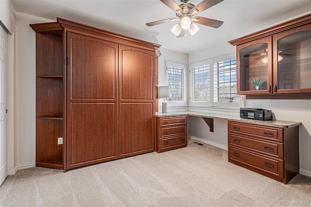 unfurnished office featuring built in desk, light colored carpet, and visible vents