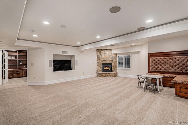 living area featuring recessed lighting, light carpet, and a stone fireplace