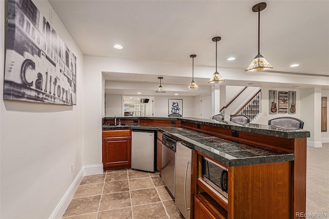 kitchen with baseboards, recessed lighting, a sink, stainless steel appliances, and decorative light fixtures