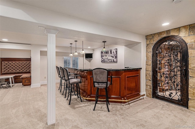 bar with decorative light fixtures, light colored carpet, arched walkways, and a bar