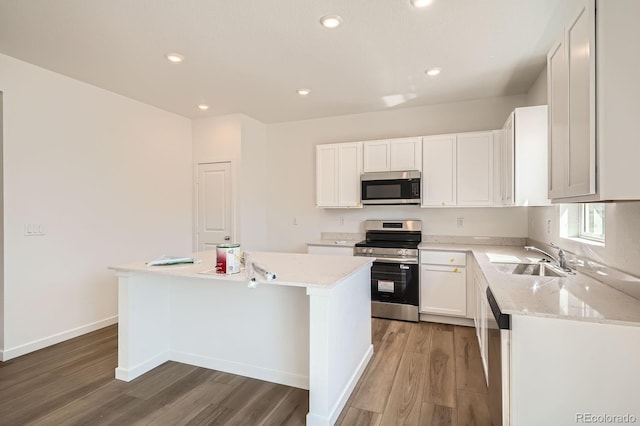 kitchen with appliances with stainless steel finishes, a sink, light wood-type flooring, a center island, and recessed lighting