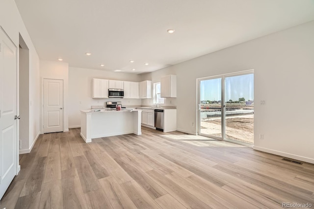 kitchen featuring appliances with stainless steel finishes, white cabinets, light wood-style flooring, light countertops, and recessed lighting