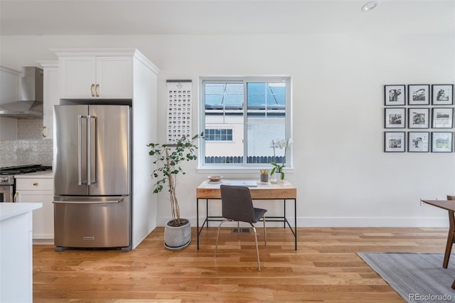 2571 S Cherokee St, Denver, CO 80223 - kitchen with appliances with stainless steel finishes, wall chimney exhaust hood, white cabinetry, light wood finished floors, and tasteful backsplash
