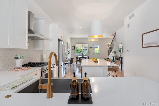 2571 S Cherokee St, Denver, CO 80223 - kitchen featuring wall chimney exhaust hood, appliances with stainless steel finishes, a center island, and white cabinets