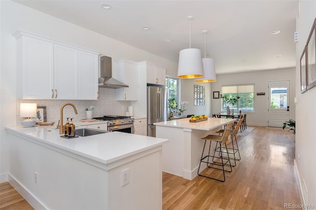 2571 S Cherokee St, Denver, CO 80223 - kitchen with wall chimney range hood, high quality appliances, a center island, light wood-type flooring, and recessed lighting