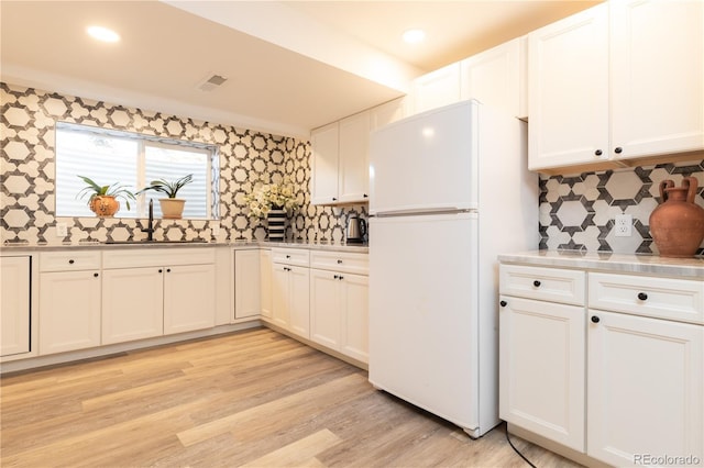 5298 Pony Creek Cir, Colorado Springs, CO 80919 - kitchen with freestanding refrigerator, white cabinetry, decorative backsplash, light countertops, and wallpapered walls