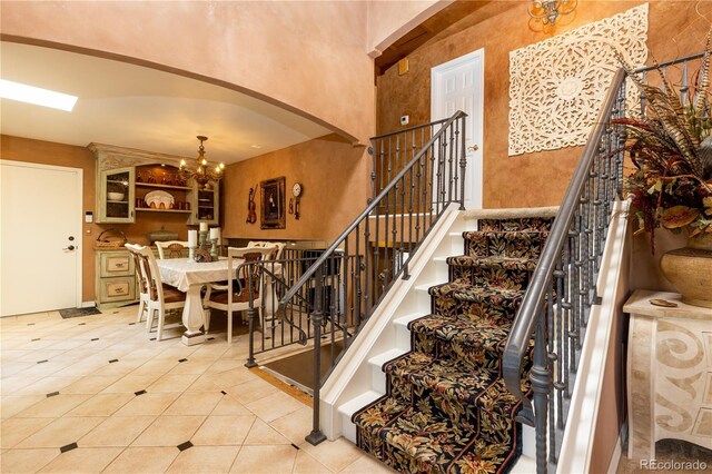 5298 Pony Creek Cir, Colorado Springs, CO 80919 - stairs featuring arched walkways, tile patterned floors, a chandelier, and a high ceiling