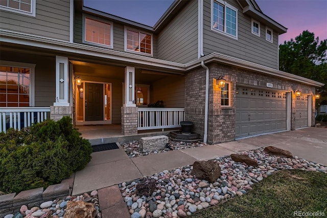 exterior entry at dusk with a garage and a porch