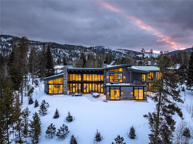 snow covered back of property with a mountain view