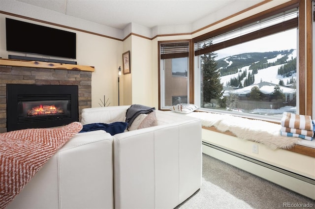 living room featuring baseboard heating, a mountain view, a stone fireplace, and carpet floors